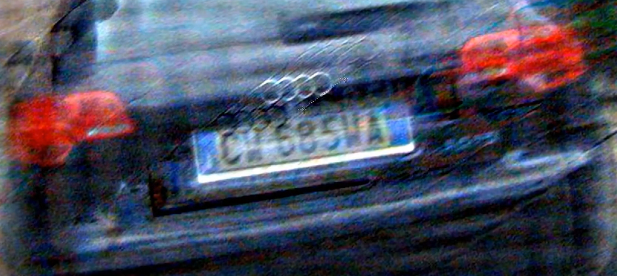 Rear of a moving sedan — enhanced